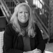Woman sitting at table, indoor setting, black and white.