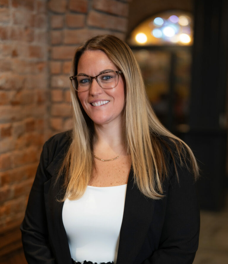 Smiling woman in business attire, standing indoors.